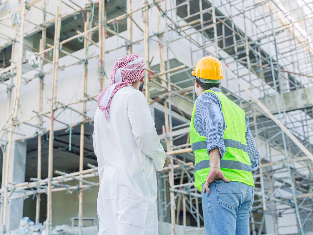 engineer-standing-with-arub-property-investor-look-2023-11-27-05-31-54-utc engineer standing with arub property investor looking under construction building for new properties projects in middle east country